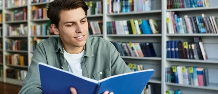 Persona estudiando en una biblioteca con libros y notas